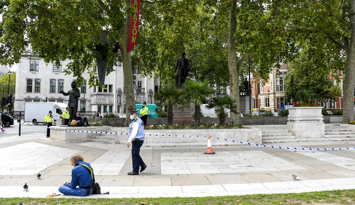 Polisi berpatroli saat aktivis Extinction Rebellion menaiki dua pohon di Parliament Square sebagai bagian dari protes perubahan iklim di London, Inggris, Selasa (8/9/2020). Menggelar aksi di tengah pandemi COVID-19, para aktivis mengenakan masker selama protes berlangsung. (AP Photo/Alberto Pezzali)