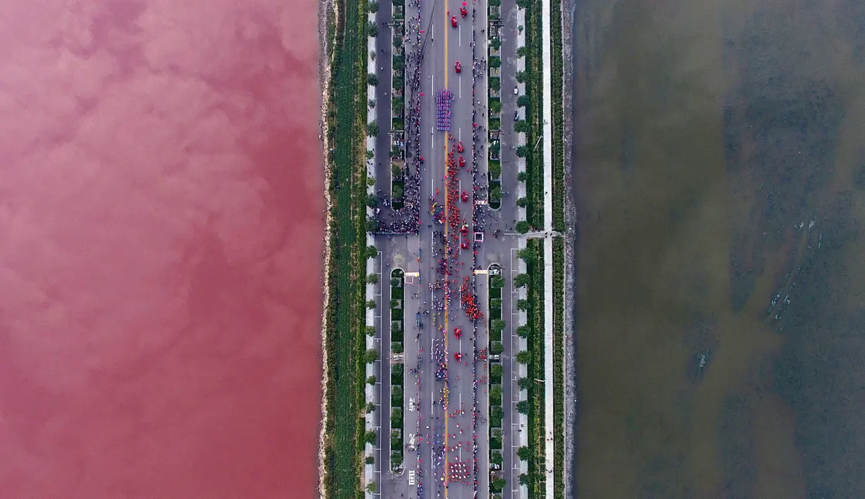 Pemandangan kontras air di sebuah danau garam yang dipisahkan oleh sebuah jalan di Yunchen, Shanxi, Tiongkok, Minggu (25/9). Fenomena aneh ini menjadi tontonan warga. (REUTERS/Wei Liang)