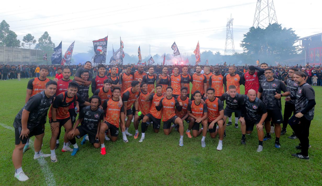 Persija Jakarta dan Persib Bandung sama-sama berpeluang menggusur posisi Borneo FC dari puncak klasemen jika salah satu tim berhasil meraih poin penuh. Tampak dalam foto, pemain Persija berfoto berlatar ribuan Jakmania yang memenuhi Persija Training Ground, Bojong Sari, Depok, Jawa Barat, Jumat (9/1/2026). (Bola.com/M Iqbal Ichsan)