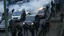 Polisi anti huru-hara mengamankan aksi pengemudi taksi yang memblokir jalan dengan membakar ban saat unjuk rasa menentang layanan transportasi VTC seperti Uber, di jalan lingkar di porte Maillot di Paris, Perancis, Selasa (26/1). (AFP PHOTO/Thomas SAMSON)