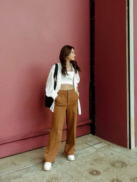 Gaya kasual untuk sekedar minum kopi di kafe atau ke toko buku. Michelle tampak mengenakan crop top yang ditumpuknya dengan oversized shirt yang sama-sama berwarna putih, dipadu dengan celana panjang cokelat, dan ia membawa tote bag hitam. Foto: Instagram.
