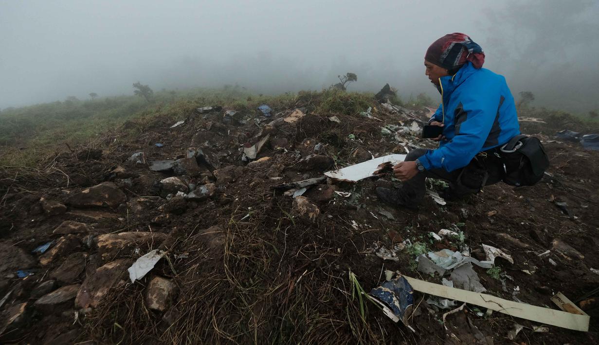 Pesawat tersebut membawa 10 orang yang terdiri dari tujuh kru dan tiga penumpang. Tampak dalam foto, seorang petugas pencarian dan penyelamatan membawa puing-puing pesawat turboprop Indonesia Air Transport berjenis ATR 42-500 di Gunung Bulusaraung, Sulawesi Selatan pada Minggu 18 Januari 2026. (Muchtamir Zaide/AFP)