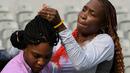 Petenis putri AS, Venus Williams, merapikan rambut adiknya, Serena Williams, saat latihan jelang Olimpiade Rio 2016 di Olympic Tennis Center, Rio de Janeiro, Brasil, (3/8/2016). (AFP/Luis Acosta)