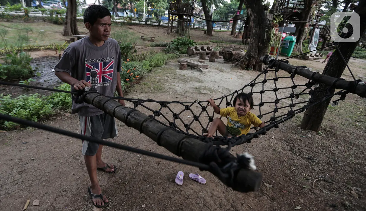 Seorang anak ditemani orang tuanya bermain di Taman Tomang Rawa Kepa, Jakarta, Minggu (21/6/2020). Lokasi tersebut menjadi salah satu tempat alternatif liburan warga untuk menghilangkan kebosanan di tengah masa PSBB transisi. (Liputan6.com/Johan Tallo)