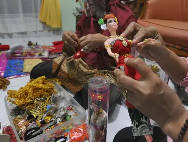 Ibu rumah tangga menyelesaikan pembuatan boneka adat Indonesia di Ammie Dolls di Komplek Pondok Tirta, Depok, Kamis (13/08/2020). Pada masa pandemi ini produksi dan penjualan anjlok hingga 95 persen menyebabkan perajin beralih ke bidang lain untuk mencukupi kebutuhan hidup. (merdeka.com/Arie Basuki)