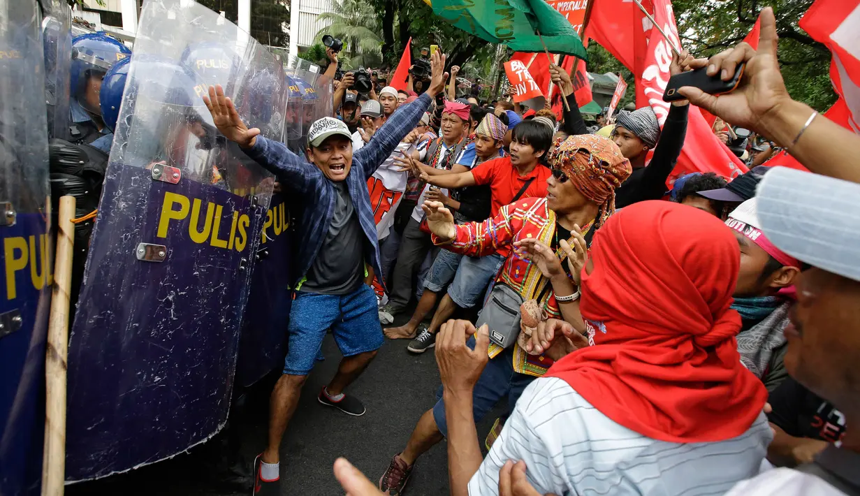 Seorang pria berusaha mencegah bentrokan antara polisi dan demonstran saat aksi di dekat Kedutaan Besar AS di Manila, Filipina (11/11). Mereka menggelar aksi untuk memprotes kunjungan Presiden AS, Donald Trump ke Filipina. (AP Photo/Aaron Favila)