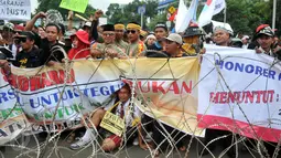 Massa dari Forum Honorer Kategori 2 (FHK2I) membentangkan spanduk saat unjuk rasa di depan Istana Merdeka, Jakarta, Rabu (10/2). Guru honorer dari seluruh Indonesia itu menuntut Pemerintah agar mengangkat mereka sebagai PNS. (Liputan6.com/Gempur M Surya)