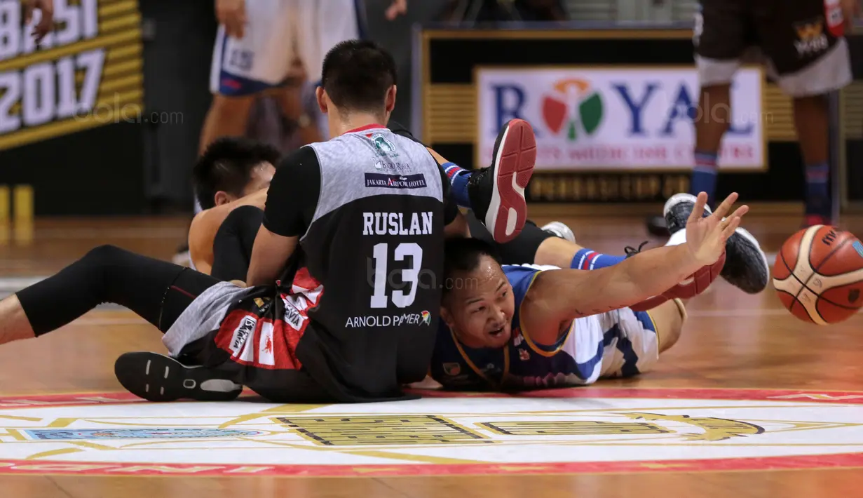 Pebasket Satria Muda, Arki Wisnu (kanan) terjatuh saat berebut bola dengan pebasket Aspac Jakarta, Ruslan dan Prastawa pada laga Perbasi Cup 2017 di Sports Mall, Kelapa Gading, Jakarta, (09/11/2017). Satria Muda menang 86-79. (Bola.com/Nick Hanoatubun)