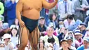 Seorang pegulat sumo melemparkan tanah ke udara sebelum bertanding dalam turnamen Honozumo di Kuil Yasukuni, Tokyo, Jepang, 15 April 2019. Ribuan penonton dari dalam dan luar negeri menikmati pertandingan dalam turnamen tersebut. (TRIBALLEAU CHARLY/AFP)