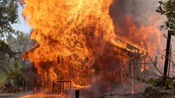 Sebuah rumah terbakar di dekat Mariposa, California(23/7/2022). Api yang bergerak cepat membakar di luar Taman Nasional Yosemite telah memaksa evakuasi, menghanguskan lebih dari 11.500 hektar dan telah menghancurkan beberapa rumah sejak mulai Jumat sore. (Justin Sullivan/Getty Images/AFP)