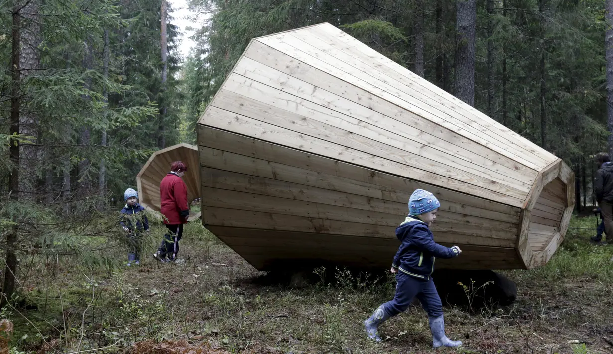 Pengunjung bermain di dekat megafon raksasa dari kayu buatan sekelompok mahasiswa arsitektur interior di dalam hutan Estonia, 28 September 2015. Megafon ini dibuat untuk mendengarkan suara hutan dan mahluk yang tinggal di dalamnya (REUTERS/Ints Kalnins)