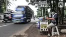 Feri (28) saat menyelesaikan jasa servis kartu tanda penduduk (KTP) di Jakarta, Kamis (21/1/2021). Bermodal meja lipat, poster, dan peralatan pendukung seperti lem, korek api, serta plastik laminating, Feri membuka jasa servis kartu identitas di pinggir jalan Ibu Kota. (merdeka.com/Iqbal S. Nugroho)