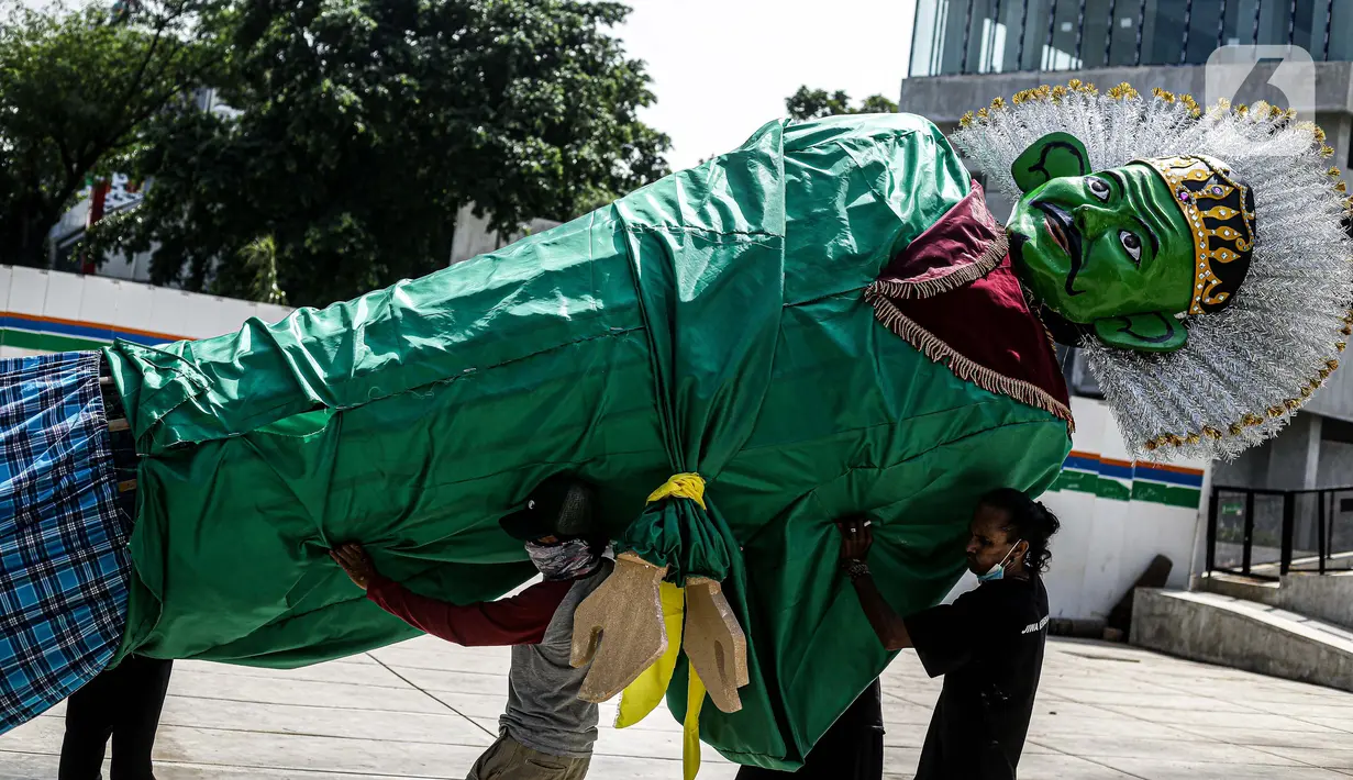 Sejumlah pekerja membawa ondel-ondel untuk dipasang di Taman Ismail Marzuki (TIM), Jakarta, Selasa (22/6/2021). Sebanyak 10 ondel-ondel raksasa setinggi 4,94 meter akan dipamerkan di TIM saat peringatan HUT ke-494 DKI Jakarta yang berlangsung dari 22 hingga 30 Juni 2021. (Liputan6.com/Faizal Fanani)