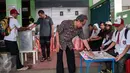 Warga menggunakan hak pilihnya pada Pilkada DKI 2017 di TPS 45 Kelurahan Kebon Pala, Jakarta, Rabu (15/2). Petugas di TPS tersebut menggunakan kostum seragam sekolah dasar untuk menarik warga datang ke TPS. (Liputan6.com/Gempur M Surya)