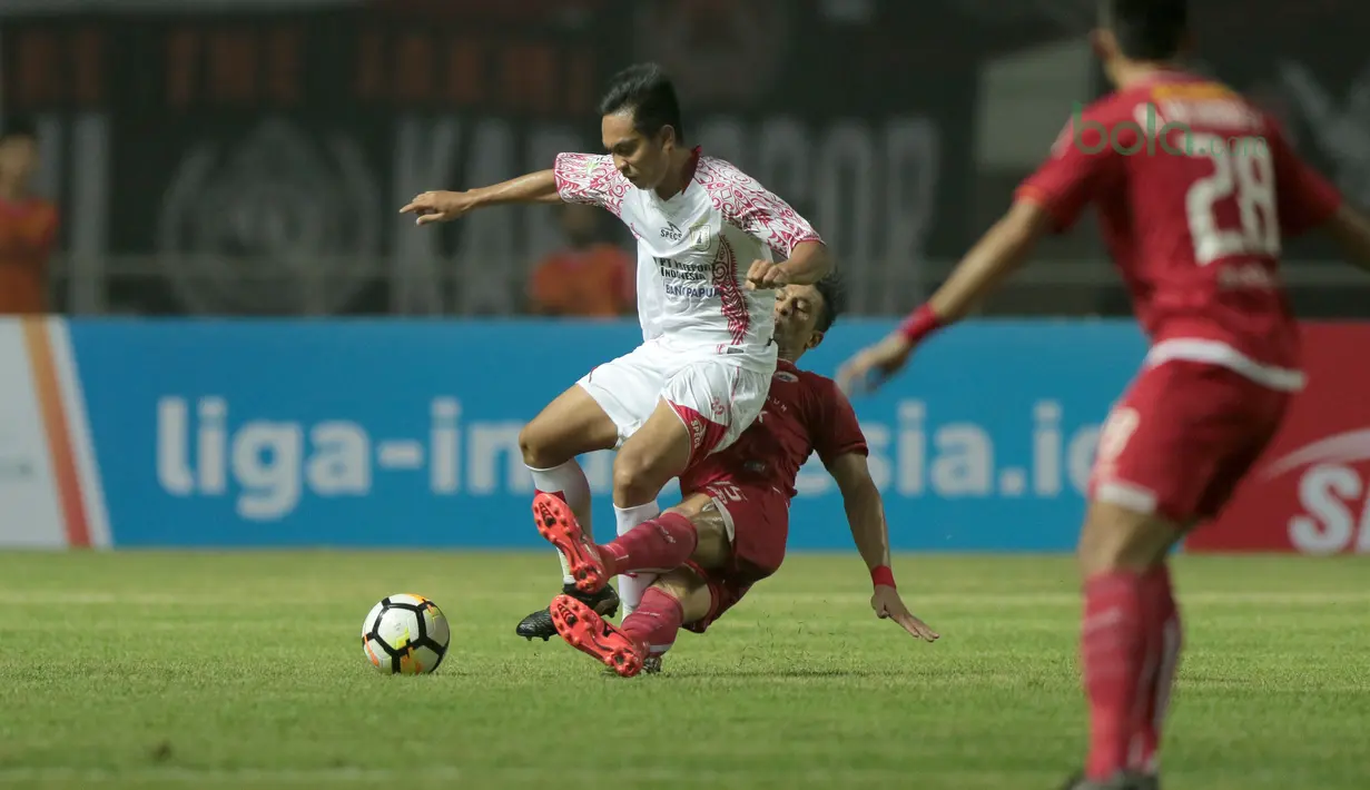 Addison Alves (bawah) menghalau bola dari kaki pemain Persipura Jayapura, Muhammad Tahir pada lanjutan Liga 1 Gojek bersama Bukalapak di Stadion Pakansari, Bogor, (25/5/2018).  Persija menang 2-0. (Bola.com/Nick Hanoatubun)