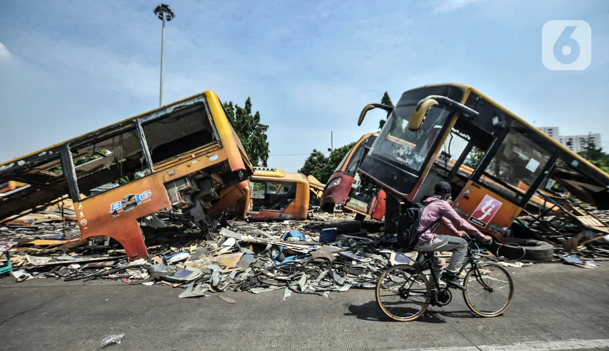 Pesepeda melintas dekat dekat 'kuburan' bus Transjakarta di Terminal Pulogadung, Jakarta, Kamis (8/7/2021). Puluhan bus Transjakarta generasi pertama yang mulai beroperasi pada 2004 silam kini terbengkalai di Terminal Pulogadung. (merdeka.com/Iqbal S. Nugroho)