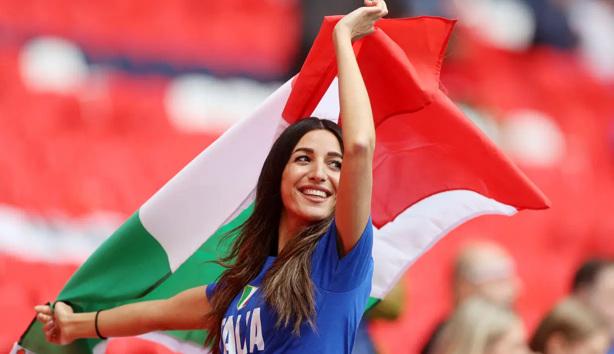 Suporter Timnas Italia mengibarkan bendera saat menyaksikan pertandingan melawan Spanyol pada laga semifinal Euro 2020 di Stadion Wembley, Rabu (7/7/2021). (Foto:AFP/Carl Recine,Pool)