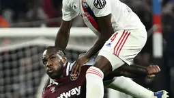 Bek Olympique Lyon Castello Lukeba (atas) berebut bola dengan gelandang West Ham United Michail Antonio pada leg kedua perempat final Liga Europa melawan Lyon di Parc Olympique Lyonnais, Jumat (15/4/2022) dini hari WIB. West Ham lolos ke semifinal usai melibas tuan rumah Lyon 0-3. (Jeff PACHOUD/AFP)