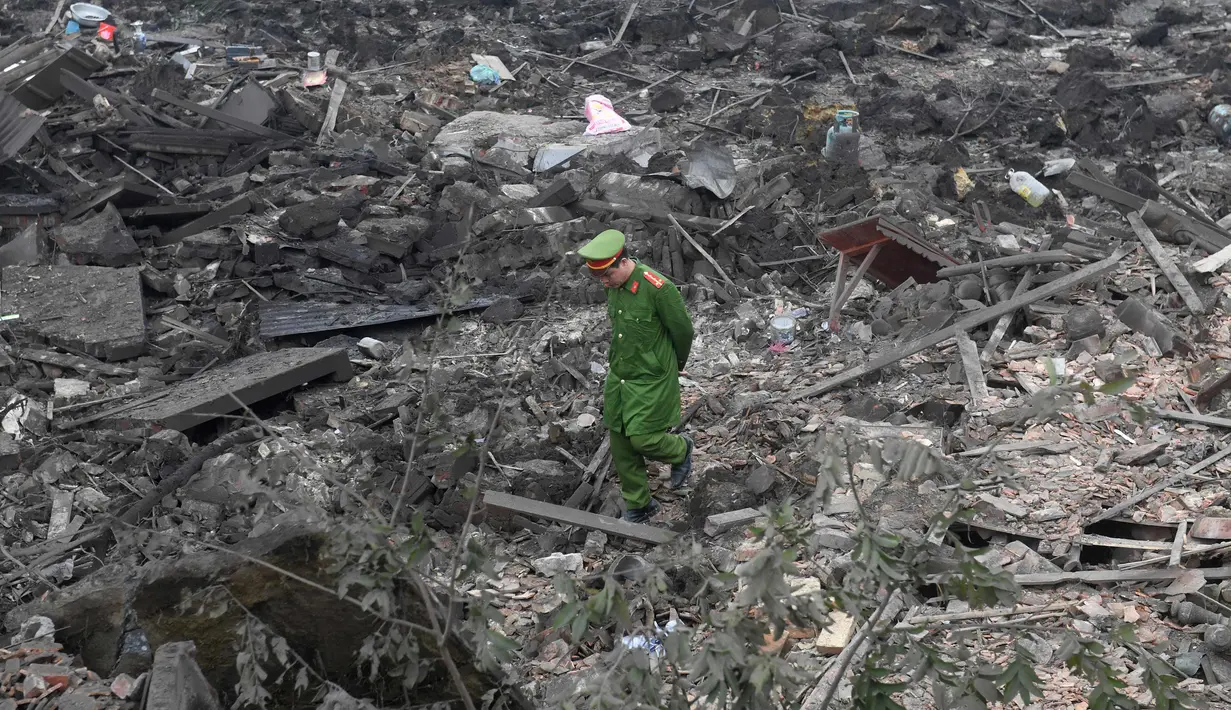 Seorang polisi berjalan melintasi puing-puing setelah sebuah ledakan besar menghancurkan lima rumah dan bangunan di sekitar provinsi utara Bac Ninh (3/1). Ledakan tersebut juga melukai enam orang lainnya. (AFP Photo/Hoang Dinh Nam)