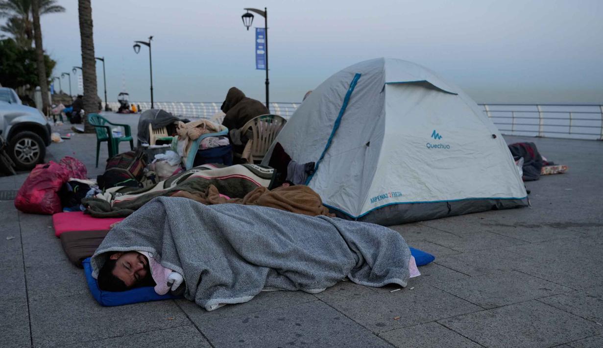 Hingga 6 Maret 2026, Kementerian Kesehatan Lebanon melaporkan sedikitnya 123 orang tewas dan ratusan lainnya luka-luka akibat rangkaian serangan ini. Tampak dalam foto, para pengungsi yang melarikan diri dari serangan udara Israel di Dahiyeh, pinggiran selatan Beirut, tidur di tepi pantai Beirut, Lebanon, Jumat, 6 Maret 2026. (AP Photo/Hussein Malla)