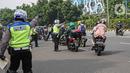 Petugas kepolisian lalu lintas memberhentikan pengendara motor saat Operasi Zebra Jaya 2020 di kawasan Cawang, Jakarta, Senin (26/10/2020). Operasi Zebra Jaya dilaksanakan pada 26 Oktober-8 November 2020 untuk menekan jumlah pelanggaran lalu lintas. (Liputan6.com/Faizal Fanani)