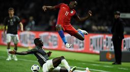 Striker Inggris, Danny Welbeck, melompat menghindari sapuan kaki pemain Jerman, Antonio Ruediger, dalam laga persahabatan di Olympiastadion, Berlin, Jerman, (26/3/2016). (AFP/Odd Andersen)
