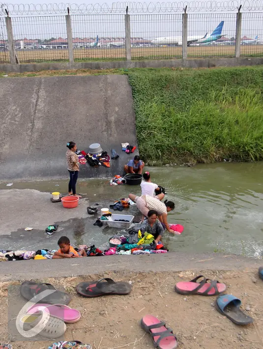 Warga mencuci pakaian di sungai yang menjadi pembatas di area Bandara Soetta, Tangerang (28/9/2015). Akibat kemarau panjang membuat pasokan air menjadi kering sehinga warga yang bermukim nekat menerobos pagar untuk mencuci. (Liputan6.com/Angga Yuniar)