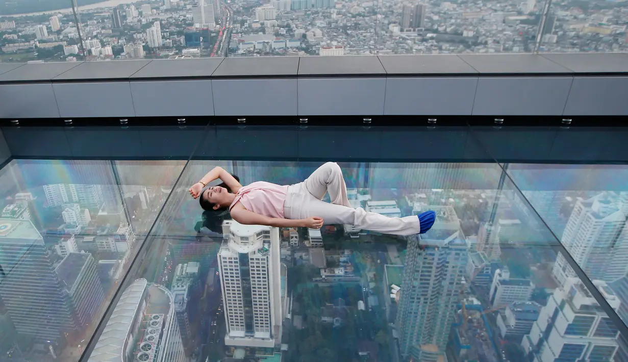 Wisatawan tiduran di dek kaca gedung King Power Mahanakhon, Bangkok, Thailand, Rabu (21/11). Gedung King Power Mahanakhon memiliki 78 lantai. (AP Photo/Sakchai Lalit)