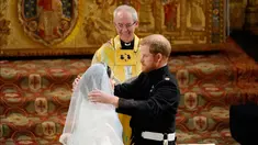 Pangeran Harry membuka tabir Meghan Markle yang disaksikan Uskup Agung Canterbury Justin Welby saat pernikahan mereka di Kapel St. George, Kastil Windsor, Inggris, Sabtu (19/5). Keduanya resmi menjadi suami istri. (Owen Humphreys/pool photo via AP)