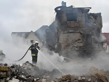 Petugas pemadam kebakaran memadamkan api di rumah-rumah pribadi yang rusak setelah serangan Rusia di wilayah Kyiv pada 25 Mei 2025, di tengah invasi Rusia di Ukraina. (Sergei SUPINSKY/AFP)