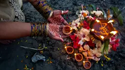 Umat Hindu India melakukan ritual selama Festival Chhath Puja di tepi sungai Brahmaputra, Gauhati, Selasa (13/11). Festival Hindu kuno ini dilakukan sebagai bentuk terima kasih kepada Dewa Matahari yang menopang kehidupan di bumi. (AP/Anupam Nath)