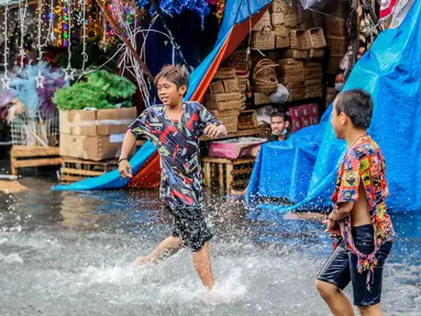 Anak-anak bermain di tengah banjir usai hujan deras yang tiba-tiba mengguyur di sebuah pasar dekorasi Natal di Manila, Filipina (9/12/2020). (Xinhua/Rouelle Umali)