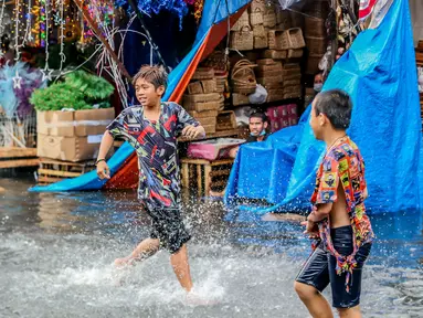 Anak-anak bermain di tengah banjir usai hujan deras yang tiba-tiba mengguyur di sebuah pasar dekorasi Natal di Manila, Filipina (9/12/2020). (Xinhua/Rouelle Umali)