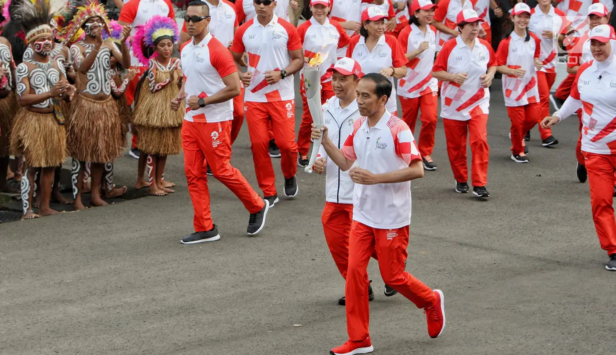 Presiden Joko Widodo didampingi Menpora Imam Nahrawi membawa api obor Asian Games 2018 sebelum upacara penurunan Bendera Merah Putih di Istana Negara Jakarta, Jumat (17/8). (Liputan6.com/Pool/Eko)