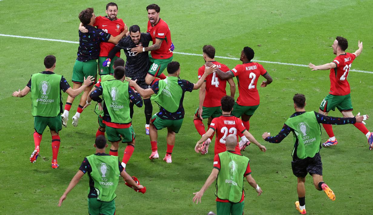Kiper Portugal, Diogo Costa bersama rekan-rekannya merayakan kemenangan atas Slovenia pada babak adu penalti saat babak 16 besar Euro 2024 di Frankfurt Arena, Frankfurt, Jerman, Senin (02/07/2024) WIB. (AFP/Daniel Roland)