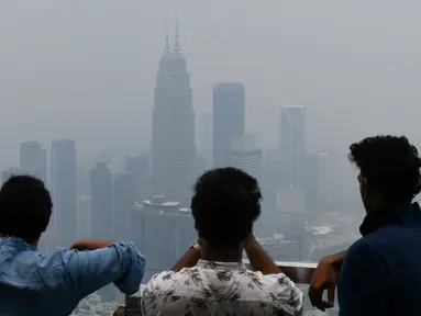 Wisatawan melihat cakrawala Kuala Lumpur, termasuk Menara Kembar Petronas, yang diselimuti kabut asap di Kuala Lumpur (11/9/2019). Kualitas udara turun ke tingkat "tidak sehat" di  sekitar Kuala Lumpur, menurut indeks polusi udara pemerintah. (AFP Photo/Mohd Rasfan)