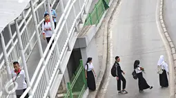 Sejumlah pelajar menyeberang di bawah JPO di Jakarta, Kamis (19/11). Selain membahayakan keselamatan, perilaku buruk pejalan kaki tersebut juga menjadi salah satu penyebab kemacetan di Ibu Kota. (Liputan6.com/Immanuel Antonius)