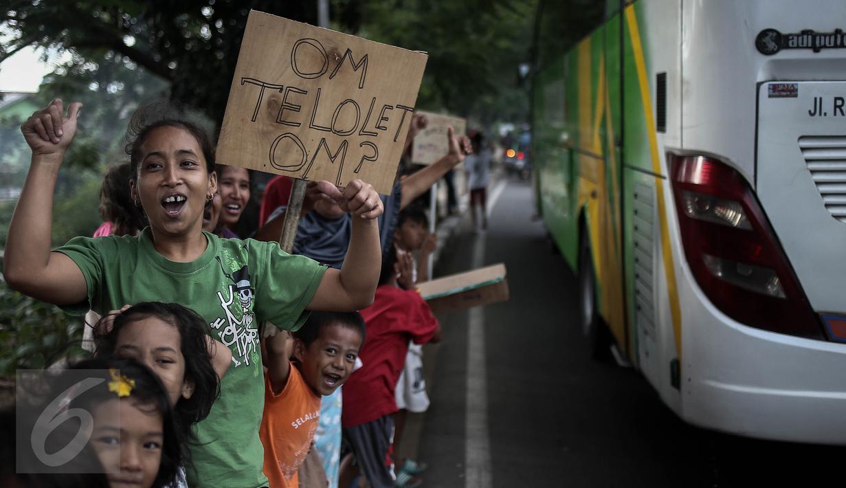 Ekspresi anak-anak saat  meminta bunyi klakson telolet ke bus yang lewat di Jalan Raya Bogor, Jakarta, Sabtu (24/12). Fenomena ini mendunia setelah beberapa artis dan tokoh terkenal dunia berkomentar di media sosial. (Liputan6.com/ Faizal Fanani)
