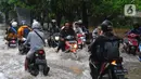 Sejumlah pengendara motor melintasi banjir di Jalan Benteng,  Duta Kranji, Kalibaru, Bekasi, Jawa Barat, Jumat (24/2/2023). Jalan yang dilalui oleh para pengendara masih digenangi air ditambah dari luapan kalibaru Duta Kranji akibat hujan deras yang mengguyur Kota Bekasi sejak Kamis (23/2/2023) malam. (merdeka.com/Imam Buhori)