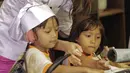 Artis Nia Ramadhani memasak bersama dua orang anak PAUD di Jakarta, Kamis (22/2). Nia bersama anggota Girls Squad lainnya memasak makan siang bersama untuk dihidangkan kepada anak PAUD. (Liputan6.com/Faizal Fanani)