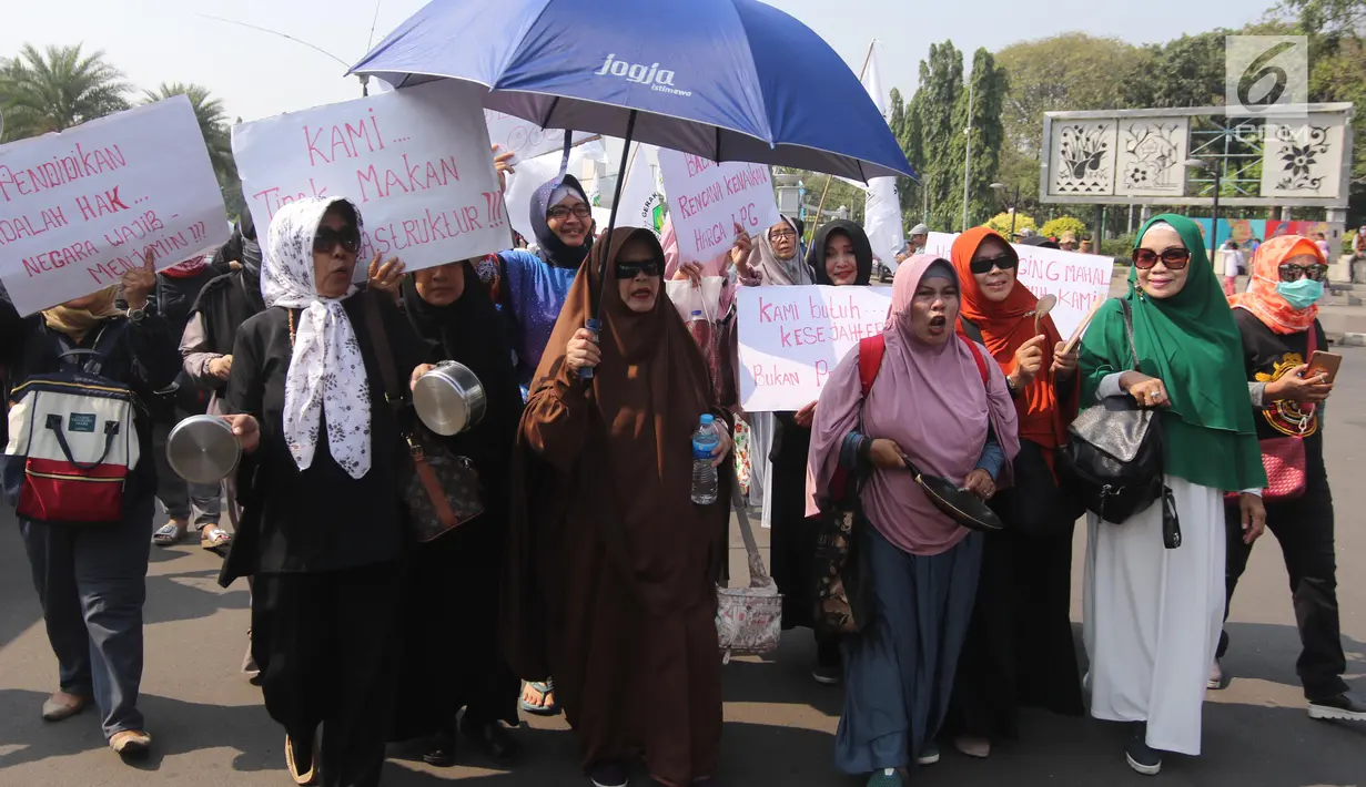 Sejumlah ibu-ibu yang tergabung dalam Barisan Emak-Emak Militan Indonesia menggelar aksi di seberang Istana Merdeka, Jakarta, Rabu (18/7). Dalam aksinya, emak-emak ini  membawa peralatan memasak seperti penggorengan dan panci. (Liputan6.com/Arya Manggala)