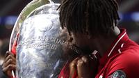 Penyerang Liverpool, Divock Origi, mencium trofi usai menjuarai Liga Champions 2019 di Stadion Wanda Metropolitano, Madrid, Minggu (2/6). Liverpool menang 2-0 atas Tottenham Hotspur. (AP/Manu Fernandez)