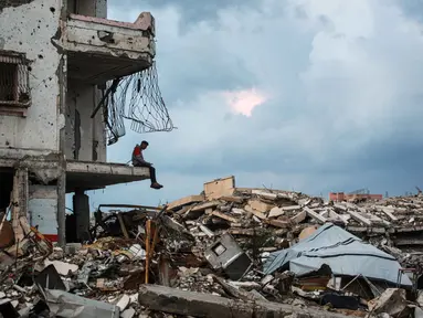 Seorang pria duduk di tepi reruntuhan bangunan di lingkungan Al-Saftawi, sebelah barat kota Jabalia, Jalur Gaza utara pada Rabu 10 Desember 2025. Secara keseluruhan, Kota Jabalia, termasuk lingkungan Al-Saftawi, digambarkan sebagai kota hantu. (BASHAR TALEB/AFP)