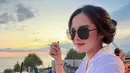Menikmati senja di pinggir pantai, Bella Bonita memilih gaya simpel dengan kemeja putih. Kemeja putih polos lengan panjang terlihat membentuk tubuhnya dengan sempurna. Foto: Instagram.