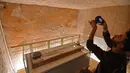 Seorang pria mengambil gambar Mumi Raja Tutankhamun di makam bawah tanahnya (KV62) di Lembah Para Raja, Luxor, Mesir (31/1). Makam terkenal tersebut menjalani konservasi sembilan tahun oleh tim spesialis internasional. (AFP Photo/Mohamed El-Shahed)