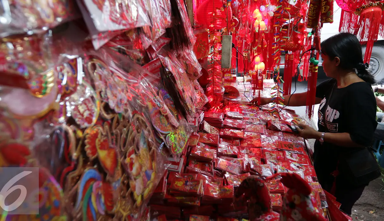 Seorang penjual pernak-pernik Imlek sedang menata dagangannya di Glodok, Jakarta, Rabu (18/01). Warna merah yang mendominasi pernak-pernik sudah menghiasi diberbagai sudut di Pasar Glodok yang mewakili suasana imlek tahun ini. (Liputan6.com/JohanTallo)