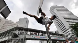 Tiang rambu lalu lintas menjadi arena aksi dari pegiat 'Pole Dance'  di Bundaran HI, Jakarta, Minggu (18/1/2015). (Liputan6.com/Miftahul Hayat)