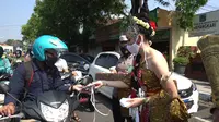 Petugas berbaju Tribuana Tungga Dewi dari Polresta Mojokerto membagikan masker kepada pengendara yang melintas. (Dian Kurniawan/Liputan6.com)