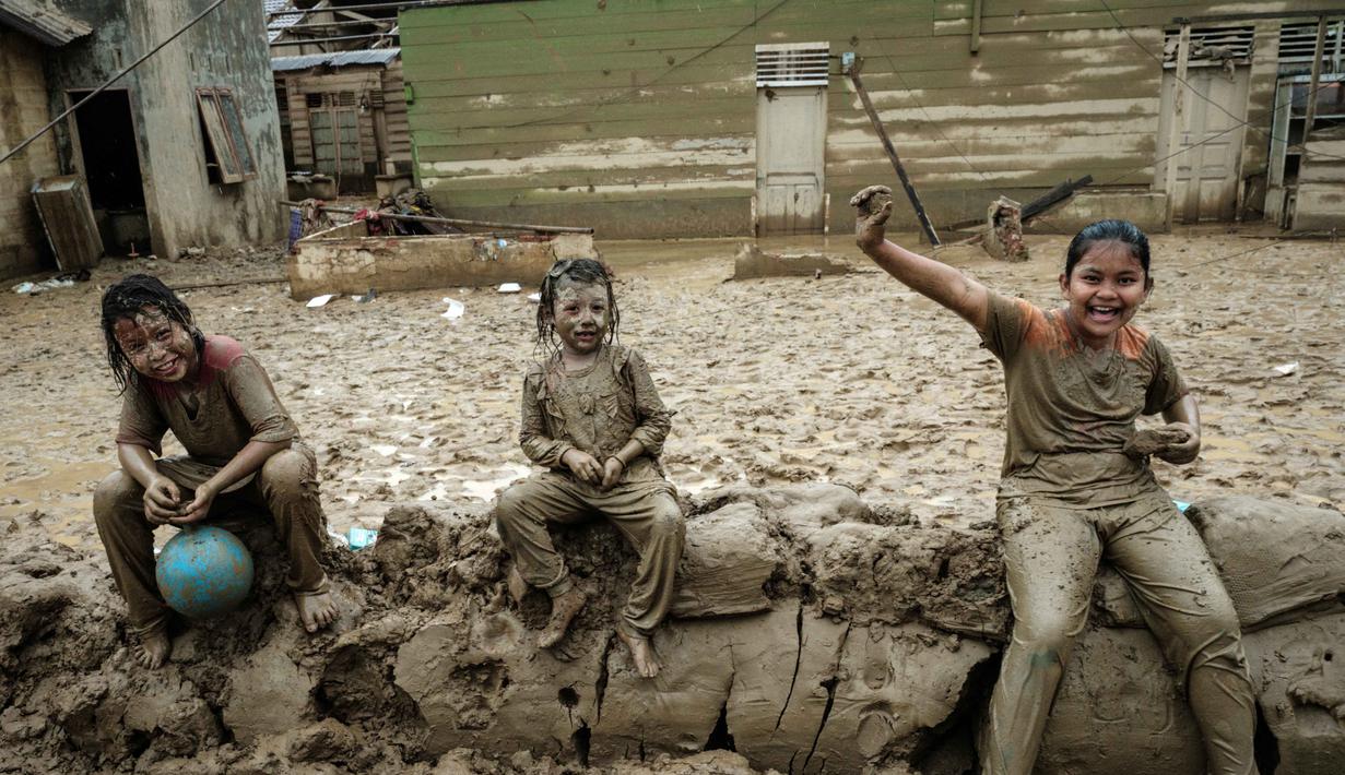 Desa ini menjadi perhatian publik karena merupakan salah satu wilayah yang terdampak paling parah akibat bencana banjir bandang di Sumatera. Tampak dalam foto, Baiti Arafah (kanan) menunggu distribusi bantuan bersama yang lain di Babo, Aceh Tamiang, pada Senin 15 Desember 2025. (Yasuyoshi Chiba/AFP)