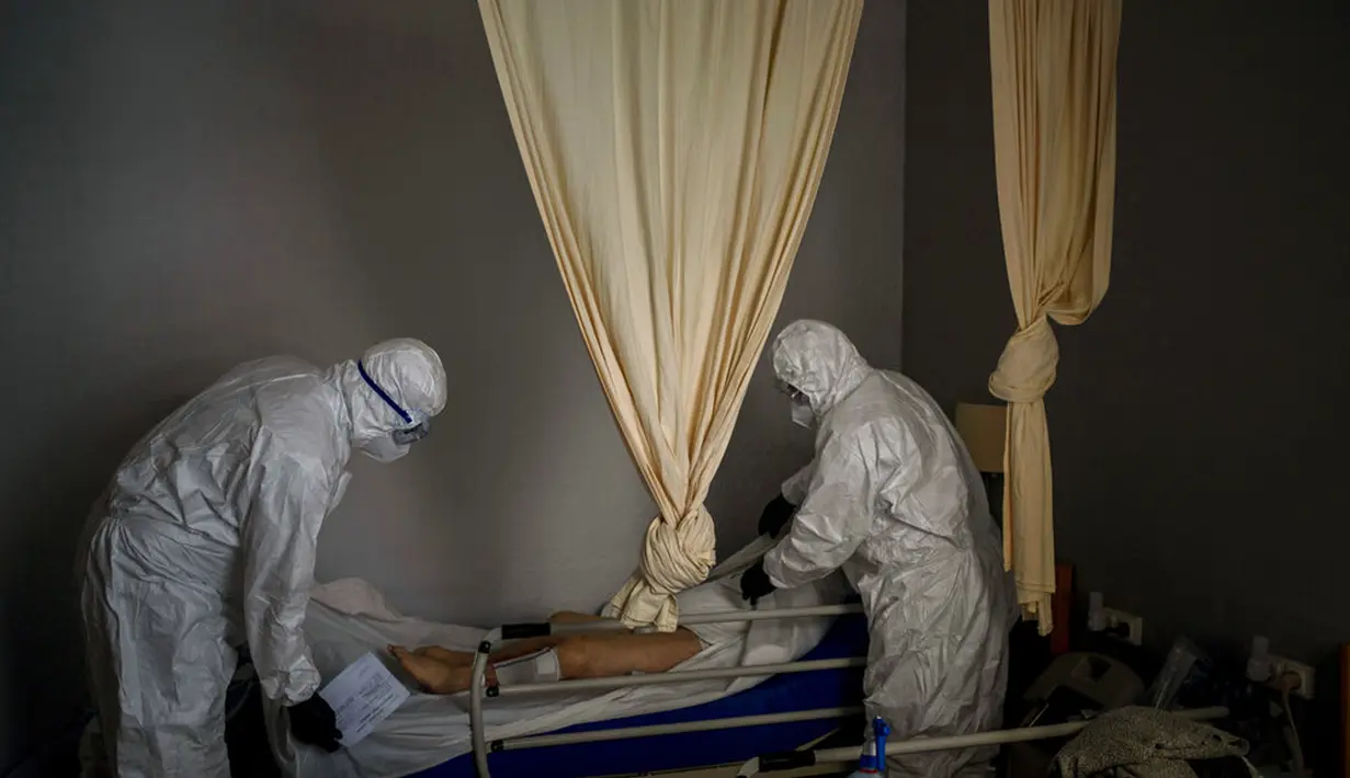 Petugas kamar jenazah mengenakan APD saat mengurus jenazah lansia yang meninggal karena COVID-19 dari panti jompo di Barcelona, Spanyol, 13 November 2020. Seperti dokter dan perawat, petugas kamar jenazah adalah bagian dari sekelompok pekerja penting di tengah pandemi. (AP Photo/Emilio Morenatti)
